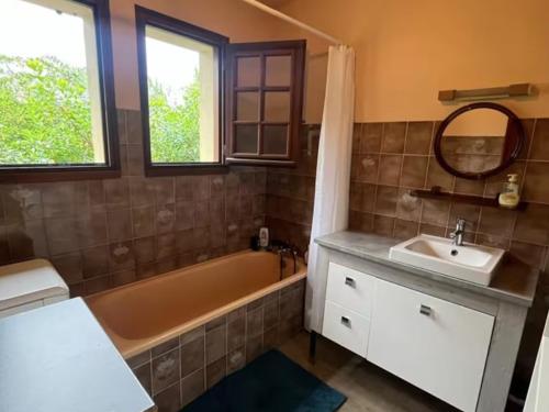 une salle de bain avec une baignoire, un lavabo et un miroir dans l'établissement Maison familiale 6 pers à 200m de la plage - FR-1-239-1133, à Capbreton