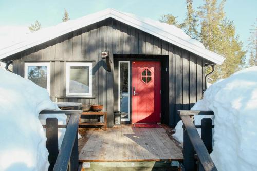 a red door on a wooden house with snow at Charming Cabin In Vikerfjell in Hønefoss