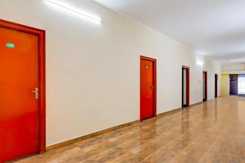 an empty hallway with red doors and wooden floors at Collection O Poigai Near Airport in Vellore
