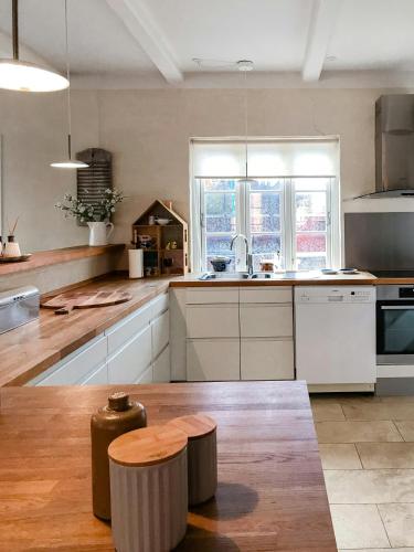 a large kitchen with white cabinets and a wooden floor at Live In Classic Skagen House In Skagen's Heart in Skagen