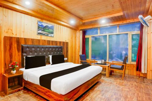 a bedroom with a large bed in a room with wooden walls at Collection O Mall Road Near Gurudwara Manali in Manāli