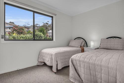 a bedroom with two beds and a large window at Unit 1 1 Jinjera Parade Pambula Beach in Pambula Beach