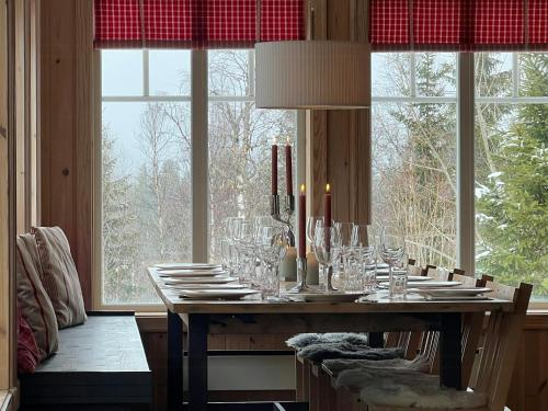 a dining room table with wine glasses in front of windows at Family Cabin With Panoramic View Near Vikerfjellet in Hønefoss