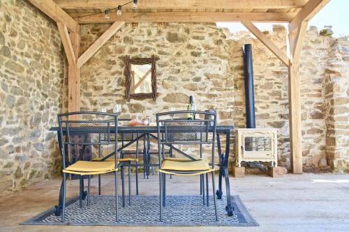 une table et des chaises dans une pièce avec un mur en pierre dans l'établissement Cozy Cottage In The Heart Of Nature, à Saint-Germain-les-Belles