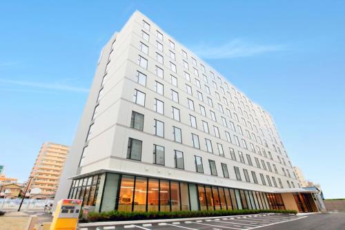 a tall white building with windows on a street at Richmond Hotel Himeji in Himeji