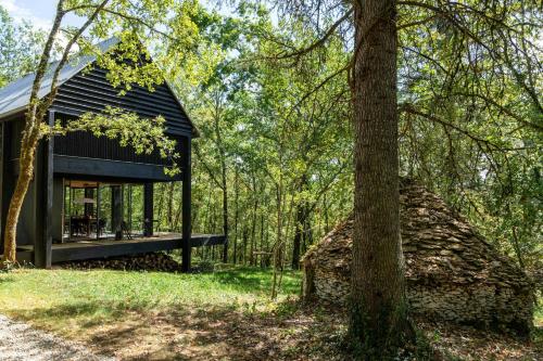 une cabane noire dans les bois avec un arbre dans l'établissement Designer House In The Vézère Forest, à Valojoulx