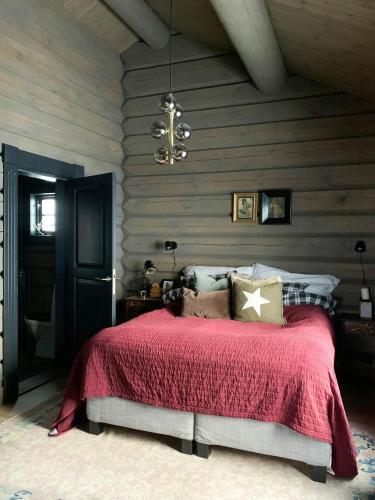 a bedroom with a bed with a red blanket at Cozy Log Cabin With A View Over Hedmarken in Løten