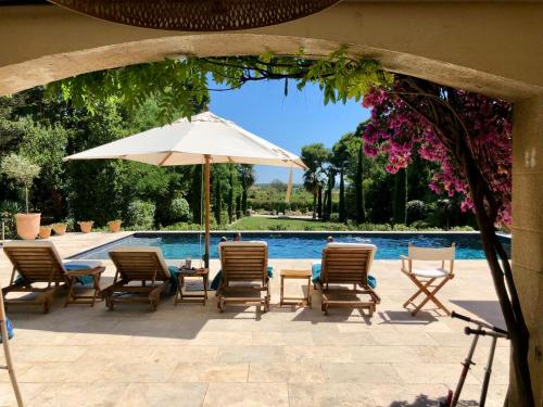 - un groupe de chaises et un parasol à côté de la piscine dans l'établissement Elegant Retreat With Pool Near Mediterranean Coast, à Florensac