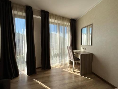 a room with a desk and large windows at Orbi Palace Bakuriani Apartment 402 in Bakuriani