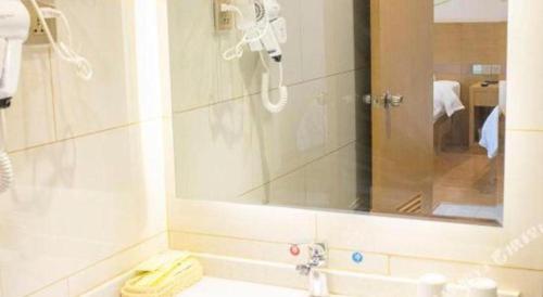 a white bathroom with a sink and a mirror at GreenTree Inn Qingdao Jiaozhou Jiaoping Road Express Hotel in Qingdao