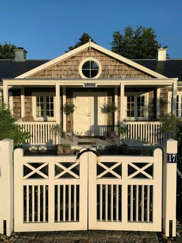 a white fence in front of a house at New England Inspired Holiday Home In Rågeleje in Vejby