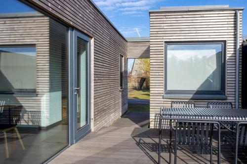 eine Terrasse mit zwei Bänken und einem Fenster in der Unterkunft Light Flooded Holiday House On The Baltic Sea in Ahrenshoop