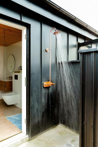 a shower with a hose on the side of a house at Newly Built Summer House With Sea View in Haderslev