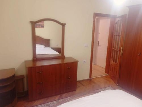 ein Schlafzimmer mit einem Spiegel auf einer Kommode in der Unterkunft Klejdo apartment in Tirana