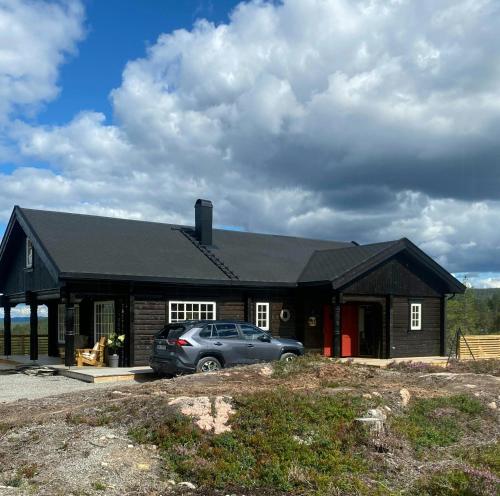 a house with a car parked in front of it at Family Cabin At Blefjell in Lampeland