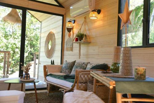 - un salon avec un canapé sur une terrasse couverte dans l'établissement Treehouse Lodge In The Dentelles De Montmirail, à Lafare