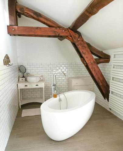 une baignoire blanche dans une salle de bain avec un lavabo dans l'établissement Family Home In The Heart Of Beaujolais, à Régnié
