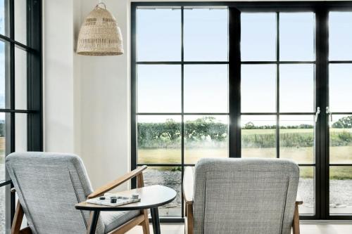two chairs and a table in a room with windows at Enjoy Nature In A Thatched Annex From 1860 in Frørup