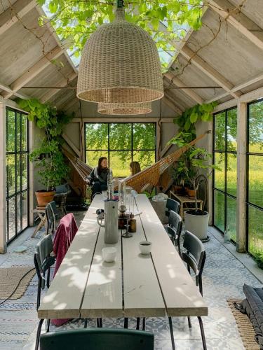 a large table in a greenhouse with people in the background at Country House With Orangery Near Mossbystrand in Rydsgård