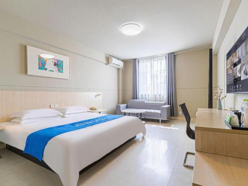 a hotel room with a large bed and a chair at Jinjiang Inn Weihai High Speed Qingdao South Road in Weihai