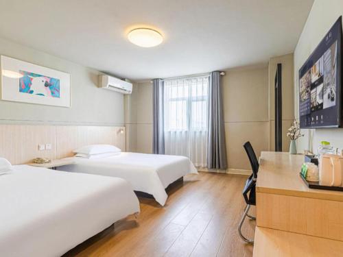 a hotel room with two beds and a desk at Jinjiang Inn Weihai High Speed Qingdao South Road in Weihai