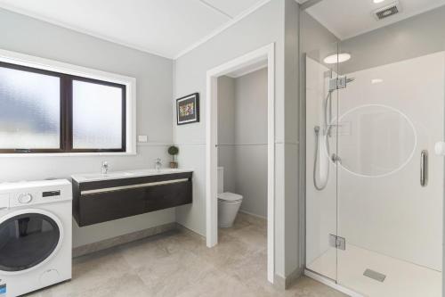 a bathroom with a sink and a washing machine at Maraetai Yacht Club in Maraetai