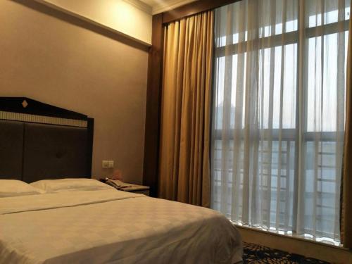 a bedroom with a bed and a large window at Zhongshan Hui Quan Hotel in Zhongshan