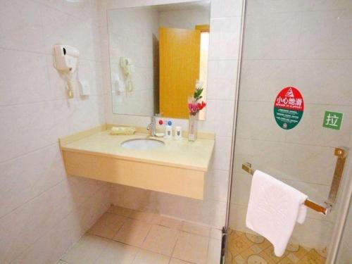 a bathroom with a sink and a mirror and a shower at GreenTree Alliance Suzhou Zhangjiagang Nanfeng Town Hotel in Zhangjiagang