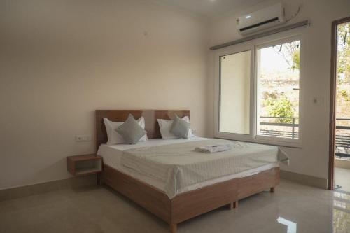 a bedroom with a bed with a large window at Mount Valley Mama Cottage in Rishīkesh