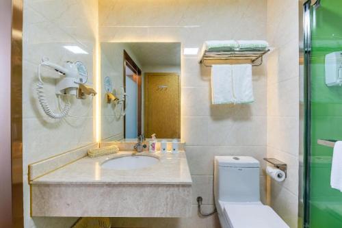 a bathroom with a sink and a toilet and a mirror at GreenTree Inn Nantong University Industrial Expo City Express Hotel in Nantong