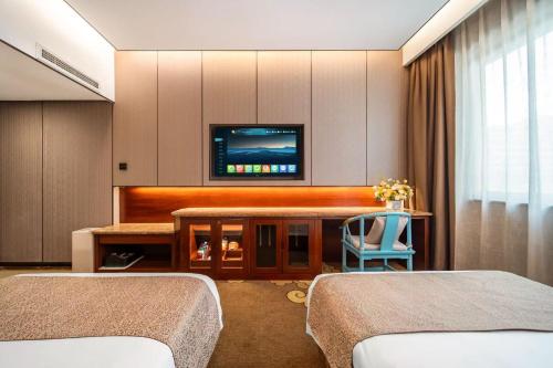 une chambre avec deux lits et une télévision à écran plat dans l'établissement Eagle City Xindi Hotel, à Zhengzhou