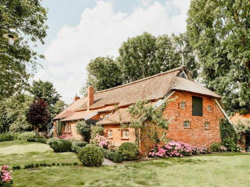 an old brick house with flowers in a yard at Tradition Meets Modern In Gulf House in Ostermarsch
