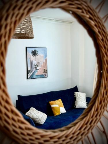 a reflection of a blue couch in a wicker mirror at L'évasion Marine à la plage 2P in Houlgate
