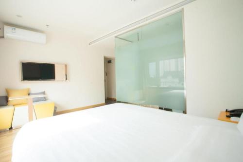 a bedroom with a white bed and a large window at 7 Days Inn Harbin West Railway Station in Harbin