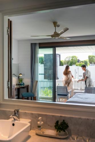 a reflection of a man and a woman in a bathroom mirror at Loligo Resort Hua Hin in Hua Hin