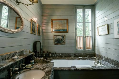 une salle de bain avec une baignoire, un lavabo et un miroir dans l'établissement Villa Between Bordeaux And Basque Coast, à Saint-Julien-en-Born