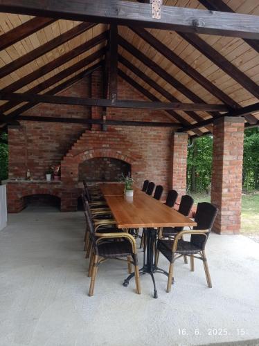 a wooden table and chairs under a brick building at Vikendica Šššuma in Srbac