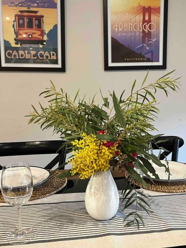 a table with a white vase with flowers on it at Lakeside Retreat Nagambie in Nagambie