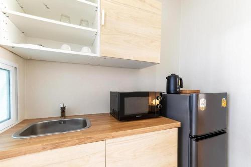 a kitchen with a sink and a microwave and a refrigerator at Sanipa Resort Rayong in Ban Noen Phra