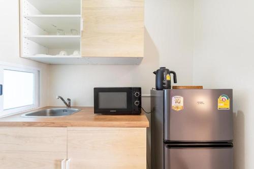 a small kitchen with a refrigerator and a microwave at Sanipa Resort Rayong in Ban Noen Phra