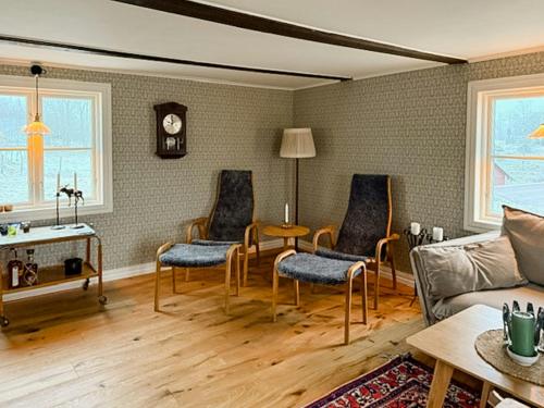 ein Wohnzimmer mit Stühlen, einem Tisch und einem Sofa in der Unterkunft Historic Cottage Near Wiredaholm in Aneby