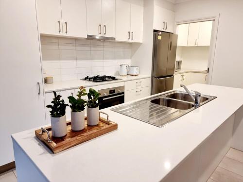 a white kitchen with a sink and some plants on a counter at Casey Green Estate 3 bedrooms Narre Warren home in Narre Warren