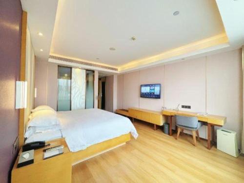 a bedroom with a bed and a desk and a tv at Lavande Hotel·Dongxing Port in Fangcheng