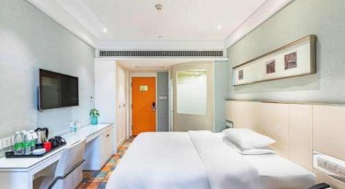 a bedroom with a large white bed and a tv at Zaozhuang Hotel in Zaozhuang
