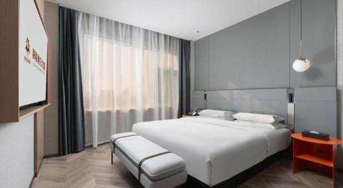 a bedroom with a white bed and a flat screen tv at Zaozhuang Hotel in Zaozhuang
