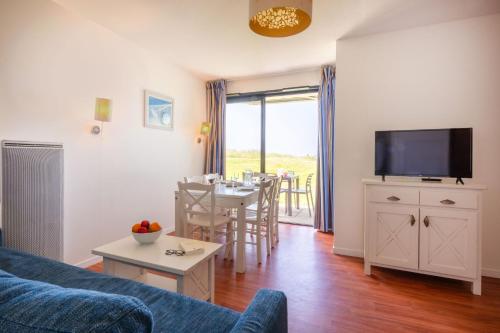 a living room with a couch and a table with a tv at Résidence Odalys Fleur de Sel in Guidel-Plage