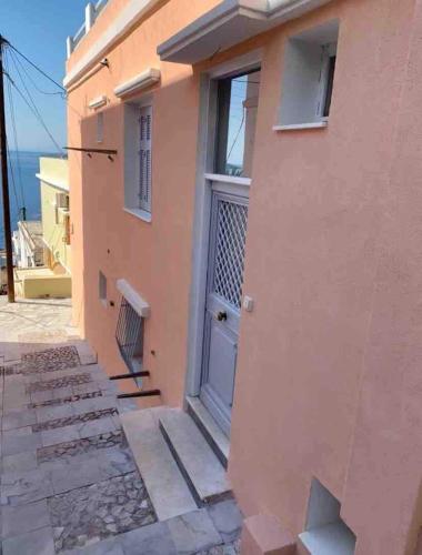 a pink house with a door and a balcony at Vaporia Terrace Seaview in Ermoupoli