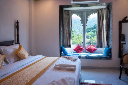 a bedroom with a bed and a large window at Raj Kunj Haveli Kumbhalgarh in Rājsamand