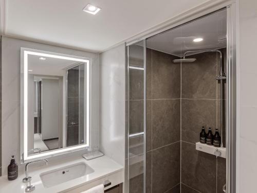 a bathroom with a shower and a sink and a mirror at NewCZ Centum Hotel in Busan
