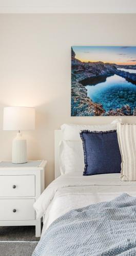 a bedroom with a white bed and a blue pillow at Summery 4BR Home by Mel Airport, CBD & Watergardens in Sydenham